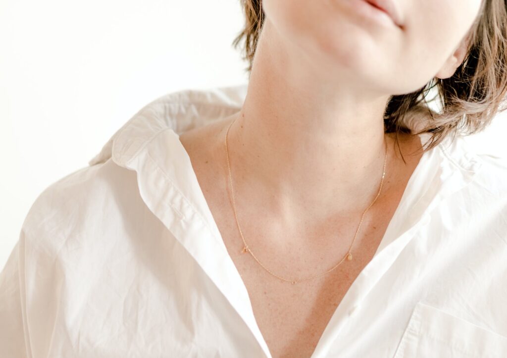 Femme portant une chemise blanche et un collier montrant son cou où se trouve la thyroïde