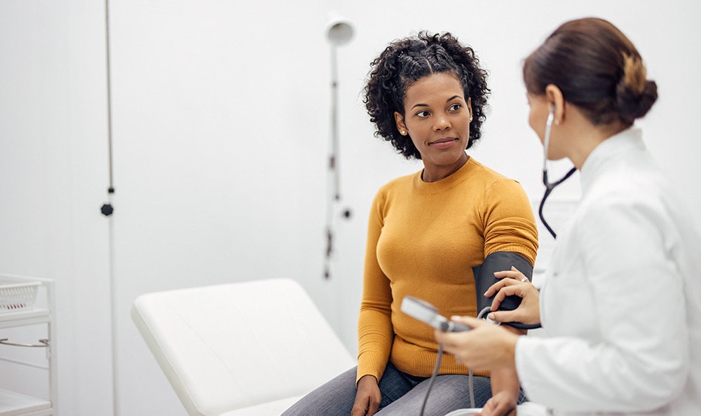 Doctor measuring blood pressure of a smiling woman.