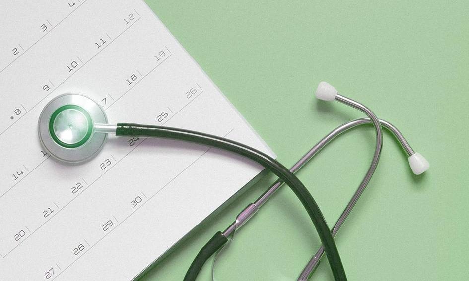 Un calendrier sur un fond bleu avec un stéthoscope posé sur le dessus pour indiquer un examen médical annuel ou un rendez-vous de suivi.