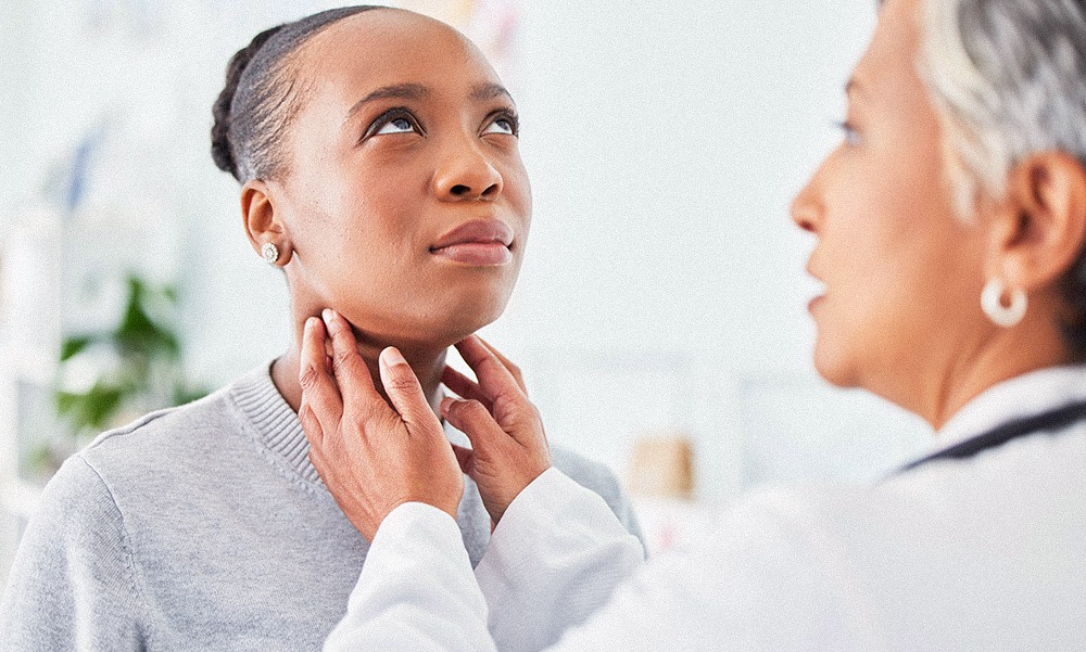 A female doctor examines the neck of a female patient in a doctors office during a thyroid check.
