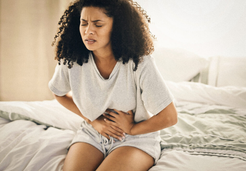 Young woman holding her abdomen due to pelvic, menstrual, ovarian pain.