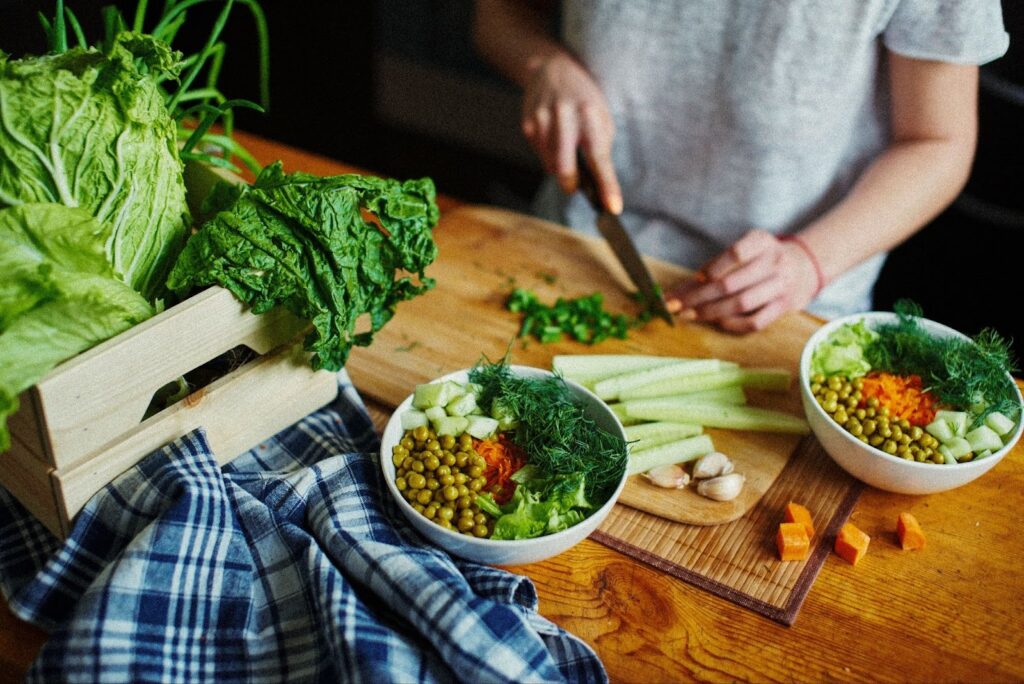 A variety of healthy foods on a kitchen countertop as someone prepares a salad.