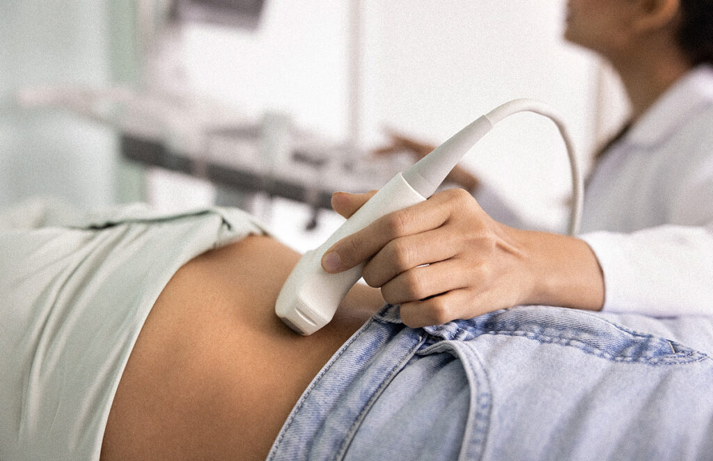 Close up female doctor using ultrasound on female patients abdomen.
